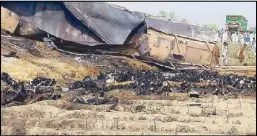  ?? AFP ?? Local residents look at burned bodies after an oil tanker caught fire following an accident on a highway in Islamabad yesterday.