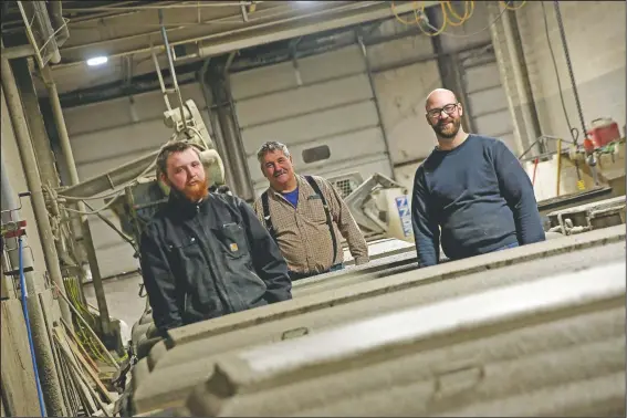  ?? (Mason City Globe-Gazette/Lisa Grouette) ?? Johnathon Rowe (from left), Daniel Clarke, and Dan Bowers stand between vault tops that were poured earlier in the day at Wilbert Burial Vault Co. in Mason City, Iowa.