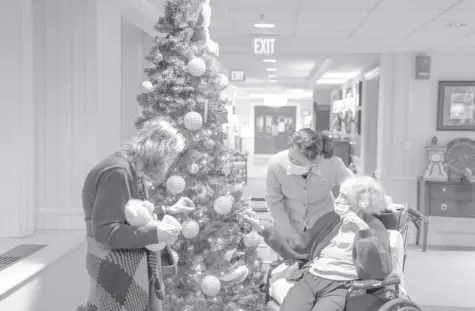  ?? AP PHOTO/NATHAN HOWARD ?? TINA SANDRI, CEO of Forest Hills of DC senior living facility, center, greets residents Cherie Neville, left, and Catherine Doleman on Thursday, December 8, 2022, in Washington. As nursing home leaders redouble efforts to get staff and residents boosted with the new vaccine version, now recommende­d for those 6 months and older, they face complacenc­y, misinforma­tion and Covid-19 fatigue.