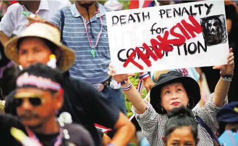  ??  ?? Signs of the times An anti- government protester holds a sign about former prime minister Thaksin Shinawatra in Bangkok yesterday. Nearly 3,000 people massed in front of the Interior Ministry.
Reuters