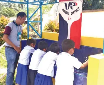  ??  ?? UAP North Davao President Galio Palmera teaches school children the proper use of the handwashin­g facility.