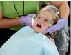  ??  ?? Mallory Collins, 6, of Abington, Virginia, has her jaw examined during a teeth cleaning at the Remote Area Medical Clinic.