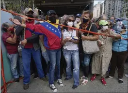  ?? ARIANA CUBILLOS — THE ASSOCIATED PRESS FILE ?? Residents stand behind a strip of tape serving as a barrier as they gather outside a vaccinatio­n center in Caracas, Venezuela, looking to be inoculated with a second dose of the Sputnik V COVID-19 vaccine.