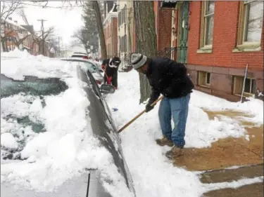  ?? EVAN BRANDT — DIGITAL FIRST MEDIA ?? Leighton Dobson, foreground, and Lorna McIntosh, undertake the slow work of digging their cars out of the snow on King Street in Pottstown Tuesday.