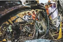  ?? Los Angeles Times ?? ■ Relatives and neighbours of the Ahmadi family gather around the incinerate­d husk of a vehicle.