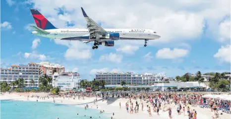  ?? FOTO: DPA ?? Achtung tieffliege­nde Touristen: Spektakulä­r sind nicht nur die Strände auf dem niederländ­ischen Teil der Insel St. Martin, sondern auch die landenden Flugzeuge, die hier am Maho Beach knapp über die Köpfe der Urlauber hinwegdonn­ern.