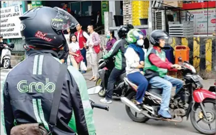  ?? GOH CHAI HIN/AFP ?? Grab Bike riders wait for passengers outside a commuter train station in Jakarta on Wednesday.