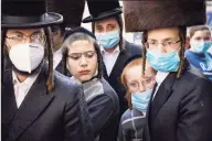  ?? John Minchillo / Associated Press ?? Members of Jewish Orthodox community gather around a journalist as he conducts an interview on a street corner Wednesday in Brooklyn.