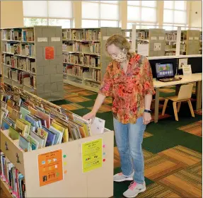  ?? Marc Hayot/Herald Leader ?? Librarian Dolores Deuel arranges some books in the children’s section of the library.