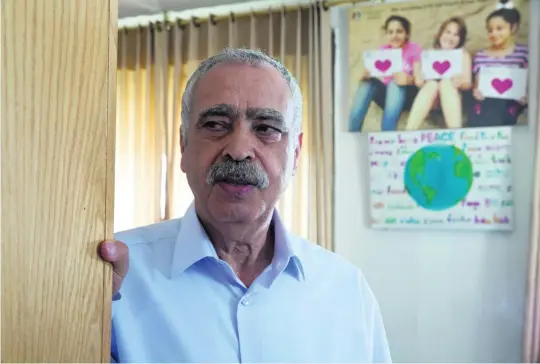  ?? Heidi Levine for The National ?? Mohammad Al Madani, head of the Committee for Interactio­n with Israeli Society, with a picture in his office displaying the word ‘peace’ in 31 languages.