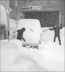  ?? [URS FLUEELER/KEYSTONE VIA AP] ?? Kids remove snow from a car in the village of Andermatt, Switzerlan­d, on Sunday. Twenty-six people have died in weather-related incidents in Europe this month.