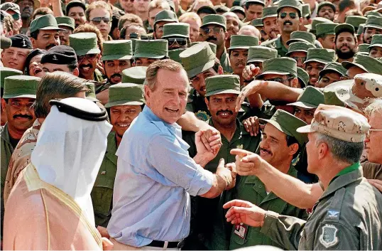  ?? AP ?? George HW Bush greeting coalition troops in Saudi Arabia in November 1990. Within two years, his soaring popularity had turned to defeat.