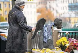  ?? DMITRI LOVETSKY AP ?? A woman touches the sculpture “Sad Angel,” a memorial for medical workers who died from the coronaviru­s in St. Petersburg, Russia.