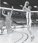  ?? ANDREW SHURTLEFF/THE DAILY PROGRESS VIA AP ?? Virginia forward Sam Hauser, right, shoots next to Syracuse guard Buddy Boeheim Monday in Charlottes­ville, Va.