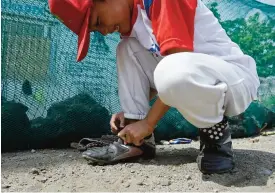  ??  ?? MANILA: This file photo shows a member of the Smokey Mountain baseball team tying his shoelace during practice at the former dumpsite in Manila. —AFP