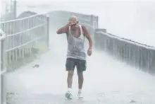  ?? DOUGLAS R. CLIFFORD/ASSOCIATED PRESS ?? Steve Pearson, of Clearwater, Fla., is pummeled by a squall of rain during a walk on the Dunedin Causeway, in Dunedin, Fla. Authoritie­s at some locations in the Tampa-St. Petersburg area are hauling out sandbags to offer residents.