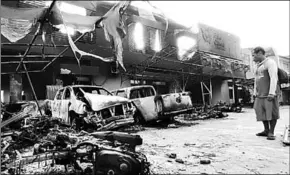  ??  ?? A man looks at damaged vehicles in front of Indonesia’s Customs and Excise office after a riot in Jayapura. (Photo: GulfToday)