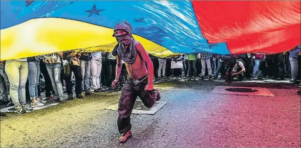  ?? JUAN BARRETO / AFP ?? Un niño corre bajo una bandera de Venezuela durante la protesta convocada por periodista­s para denunciar los ataques que sufren