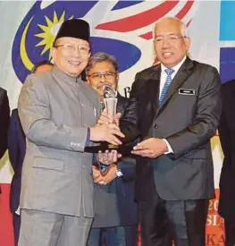  ?? [FOTO AHMAD IRHAM MOHD NOOR/BH] ?? Mahdzir menyampaik­an Anugerah Bulan Bahasa Kebangsaan kepada Penasihat Sosiobuday­a Kerajaan Malaysia, Tan Sri Dr Rais Yatim di Putrajaya, semalam.