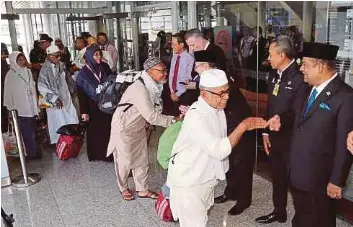  ?? [FOTO ABD RAHIM RAHMAT/BH] ?? Abdul Azeez bersalam dengan jemaah haji ketika menyambut kepulangan sebahagian dari 268 jemaah haji penerbanga­n terakhir MH8325 di KLIA, semalam.