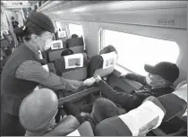  ?? ZHANG WANDE / FOR CHINA DAILY ?? A train attendant checks the temperatur­es for a passenger on the first high- speed train from Urumqi, Xinjiang Uygur autonomous region, to Xi’an, Shaanxi province, on Sunday. It is the second high- speed train route out of Xinjiang and the first one beyond Lanzhou since the Lanzhou- Xinjiang High- speed Railway was put into operation in 2014.