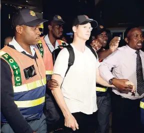  ?? AP ?? Australian cricket player Steve Smith (centre) being escorted by police officers to a departure area at OR Tambo Internatio­nal airport in Johannesbu­rg, South Africa, yesterday.