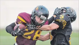  ?? BOB TYMCZYSZYN THE ST. CATHARINES STANDARD ?? Sun Devils ball carrier William Schultz (28) is defended by the Tiger-Cats’ Braydan Doucette in Football Niagara junior elite championsh­ip action Thursday night at Kiwanis Field in St. Catharines.
