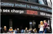  ?? SPENCER PLATT / GETTY IMAGES ?? People congregate in Times Square on Wednesday under news about former FBI Director James Comey. Comey was fired Tuesday.