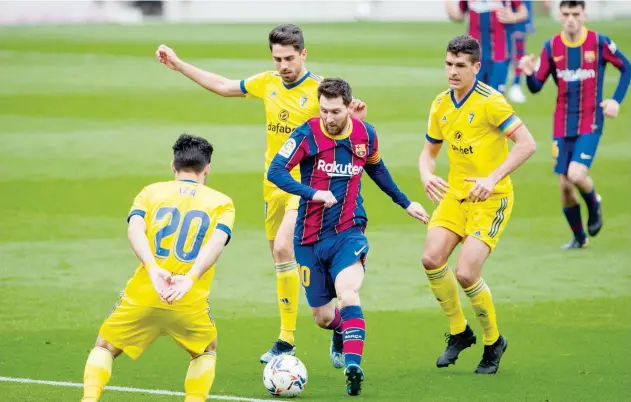  ?? Agence France-presse ?? ↑
Barcelona’s Lionel Messi (centre) controls the ball during their Spanish League match against Cadiz on Sunday.