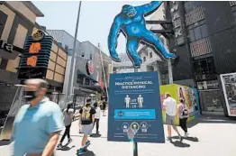  ?? MARK J. TERRILL/AP ?? People walk through Universal CityWalk on Thursday near Universal City, California.