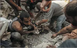  ?? THE NEW YORK TIMES ?? Palestinia­n men use their bare hands to dig for victims following an Israeli airstrike in Khan Younis that destroyed a family home in the southern Gaza Strip last year.