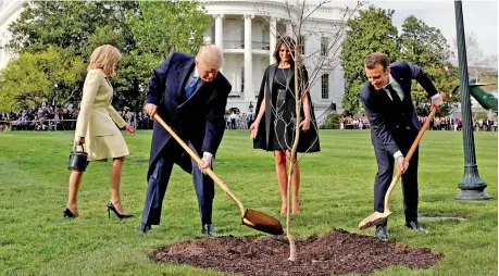  ??  ?? US President Donald Trump and French Emmanuel Macron shovel dirt onto a freshly planted oak tree as first lady Melania Trump and Brigitte Macron watch on the South Lawn of the White House, April 23, 2018. Reuters file photo