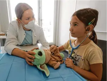  ?? Fotos: Annette Zoepf ?? Damit Kinder die Angst vor dem Krankenhau­s verlieren: Medizinstu­dentin Rebekka Prim untersucht Annas Stofftier Yoda, das starke Kopfschmer­zen hat. Anna (7) hört Yodas Herz mit dem Stethoskop ab.