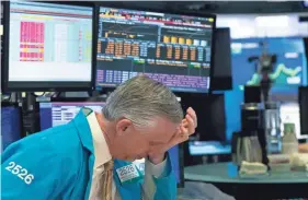  ?? MARK LENNIHAN/AP ?? A trader reacts after trading was halted at the New York Stock Exchange on Wednesday. Markets again fell steeply.