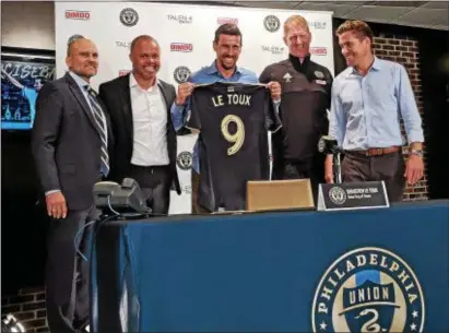  ??  ?? Sebastien Le Toux, center, holds up his ceremonial jersey after signing a one-day contract to retire with the Philadelph­ia Union. Joining Le Toux are, from left, Chief Business Officer Tim McDermott, sporting director Earnie Stewart, manager Jim Curtin...