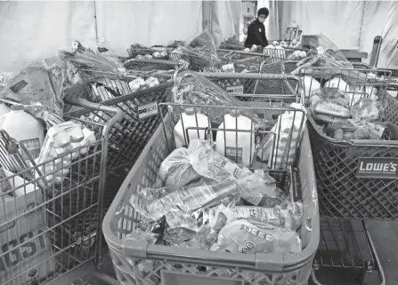  ?? PHOTOS BY BARBARA J. PERENIC/COLUMBUS DISPATCH ?? Workers fill carts with food at Mid-ohio Food Collective in Grove City, which serves 20 counties including Franklin. Agencies report they are meeting the need — shelves are not empty and people are still going home with the same amount of food, although perhaps with a few substituti­ons.