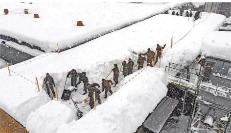  ?? FOTO: WERNER KERSCHBAU/DPA ?? Soldaten der österreich­ischen Armee befreien das Dach einer Produktion­shalle in Rosenau vom Schnee. Nur wenige Minuten nachdem sie das Dach verlassen hatten, stürzte es ein.