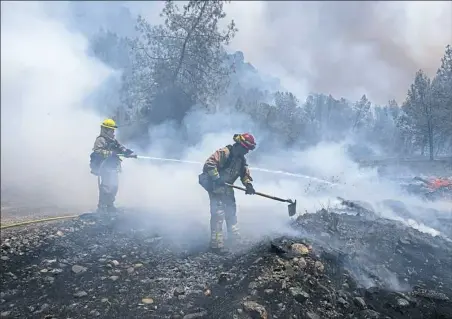  ?? Paul Kitagaki Jr./The Sacramento Bee via AP ?? Fire crews battle a wildfire Monday near Cache Creek Road in Spring Valley, Calif. Thousands were forced to flee their homes as major wildfires encroached on a charred area of Northern California still recovering from severe blazes in recent years.