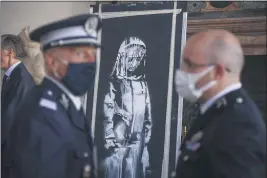  ?? PHOTOS BY DOMENICO STINELLIS — THE ASSOCIATED PRESS ?? A recovered stolen artwork by British artist Banksy depicting a young female figure with a mournful expression — painted as a tribute to the victims of the 2015 terror attack at the Bataclan music hall in Paris — is shown during a ceremony at the French Embassy in Rome on Tuesday.