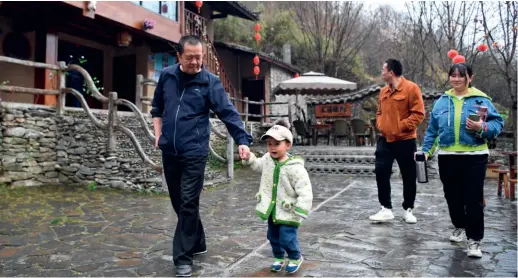  ??  ?? Visitors stroll past a guesthouse in Zhujiagou Village, Gansu Province, on March 17