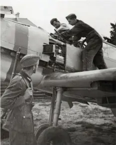  ?? (Chris Goss) ?? ■ A Wehrmacht soldier watches ground personnel of JG53 working on one of the unit’s aircraft in mid August 1940. Clearly visible is the broad red band painted around the engine cowling.