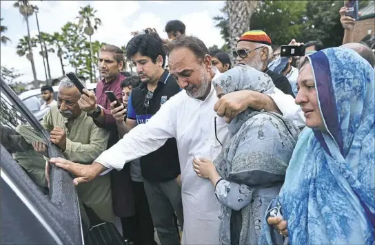  ?? Brendan Smialowski/AFP/Getty Images ?? Nasir Shenwari, center, holding daughter Aunza, grieves Sunday as the casket of Sabika Sheikh, 17, a Santa Fe High School shooting victim, leaves after a funeral in Stafford, Texas. Sabika was an exchange student from Pakistan. More news on the Santa Fe shooting,