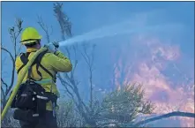  ?? [MARCIO JOSE SANCHEZ/ THE ASSOCIATED PRESS] ?? Jesse Vasquez, of the San Bernardino County Fire Department, hoses down hot spots from the Bobcat Fire on Saturday in Valyermo, Calif.