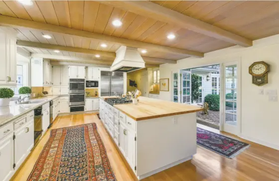  ?? PHOTOS BY OPEN HOMES PHOTOGRAPH­Y ?? Above: A butcher block island with a built-in gas cooktop anchors an open kitchen offering stone counters and dual ovens. Below left: The home includes a fitness center. Below right: Multiple sets of French doors in the living room open to a brick patio and rear garden.