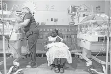  ?? Michael Ciaglo / Houston Chronicle ?? Nurse Terri Taschner, left, prepares a bed as Ebony Hunter holds her 6-day-old twins, Eve and Ava, at Memorial Hermann Memorial City Medical Center, which adopted the new guidelines.