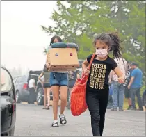  ??  ?? Members of a family whose house burned down in the Almeda fire near Medford, Ore., carry donated goods into the home where they are staying. [TREVOR HUGHES/USA TODAY NETWORK]