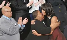  ?? | MANDEL NGAN/ AFP/ GETTY IMAGES ?? First lady Michelle Obama hugs Cleopatra Cowley- Pendleton as Nathaniel Pendleton Sr. ( left) looks on before the start of the State of the Union address on Feb. 12, 2013.