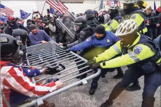  ?? John Minchillo / Associated Press ?? In this Jan. 6, 2021, file photo violent insurrecti­onists loyal to President Donald Trump hold on to a police barrier at the Capitol in Washington. A New Jersey gym owner on Friday became the first person to plead guilty to assaulting a law enforcemen­t officer during the Jan. 6 riot.