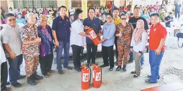  ??  ?? Victoria hands over a fire extinguish­er to Usong, witnessed by Anyi (sixth left) and Dennis (fourth left).