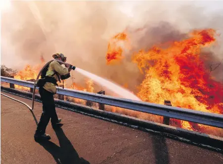  ??  ?? A firefighte­r battles a blaze along the Ronald Reagan Freeway in Simi Valley, California, on Monday.